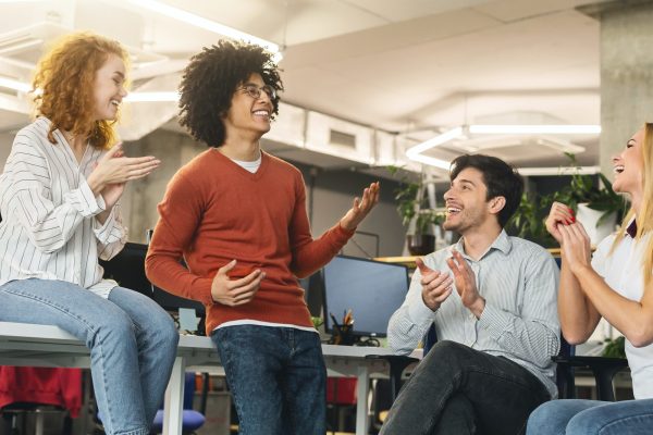 Cheerful business team greeting their successful colleague